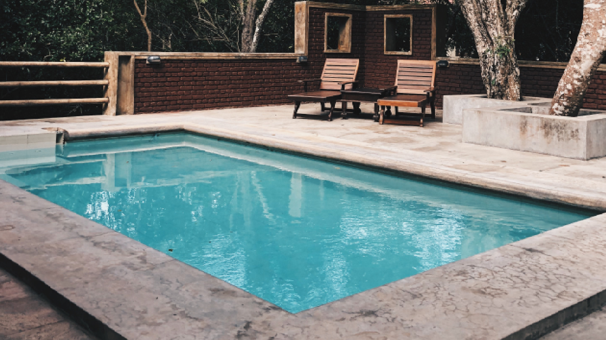 rectangle pool with reclining chairs and stone surround